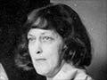 A photograph showing Annie Kelly standing in front of an easel holding a painting of Mrs Findlay