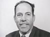 A head and shoulders portrait of a middle-aged man in a suit and tie
